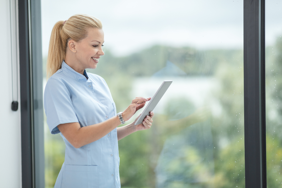 Nurse in scrubs checking notes on a tablet